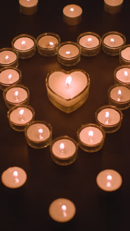 Vertical-Video-Of-Romantic-White-Candles-In-the-Shape-Of-A-Heart-On-Black-Background-2